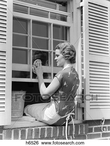 1930S Woman In Print Dress & Apron Sitting On Windowsill Washing Window With Cloth And Bucket Spring Cleaning Housewife View Large Photo Image Stock Photograph - 1930S Woman In Print Dress & Apron Sitting On Windowsill Washing Window With Cloth And Bucket Spring Cleaning Housewife. Fotosearch