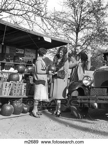1930S Women Man Roadside Produce Stand Standing Model T Car Buying Pumpkins Late Fall Fur Trim Coats View Large Photo Image Stock Photo - 1930S Women Man Roadside Produce Stand Standing Model T Car Buying Pumpkins Late Fall Fur Trim Coats . Fotosearch