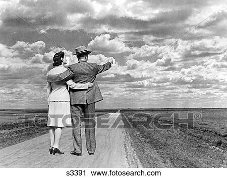 1940 1940S Couple With Arms Around Each Other Standing On Open Road In Middle Of Nowhere View Large Photo Image Stock Image - 1940 1940S Couple With Arms Around Each Other Standing On Open Road In Middle Of Nowhere . Fotosearch