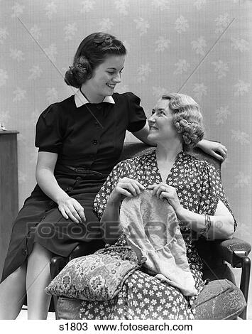 Stock Image - 1940 1940S Two Women Mother Daughter Sitting On Chair Mother Knitting . Fotosearch