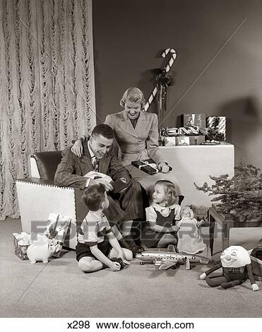 Stock Photo - 1940S 1950S Family Opening Christmas Presents . Fotosearch