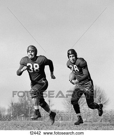 1940S 1950S Football Player Running With Ball As Defense Team Member Run Ahead View Large Photo Image Stock Image - 1940S 1950S Football Player Running With Ball As Defense Team Member Run Ahead . Fotosearch