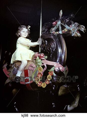 Stock Photo - 1940S 1950S Girl Riding Carousel Horse Merry Go Round . Fotosearch