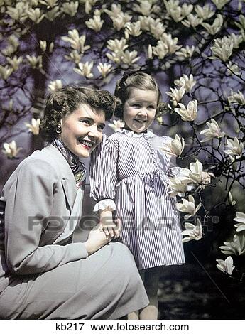 1940S 1950S Girl Woman Mother Daughter Smiling By Magnolia Blossoms Tulip Tree View Large Photo Image Stock Photo - 1940S 1950S Girl Woman Mother Daughter Smiling By Magnolia Blossoms Tulip Tree. Fotosearch