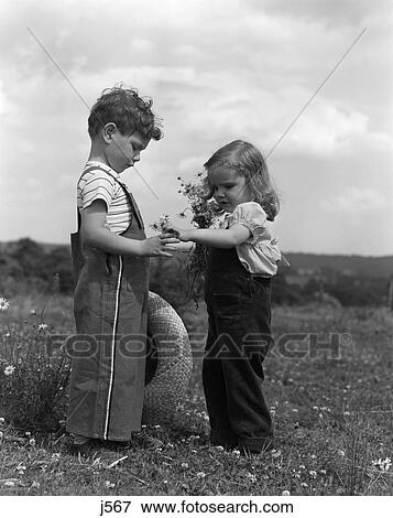 1940S 1950S Little Girl Handing Daisies To Boy Standing In Field Of Flowers View Large Photo Image Stock Photo - 1940S 1950S Little Girl Handing Daisies To Boy Standing In Field Of Flowers . Fotosearch