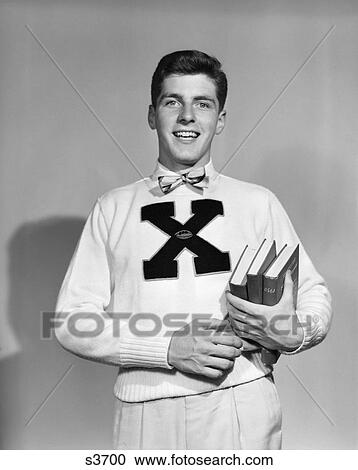 1940S 1950S Smiling 3/ 4 Length Portrait Boy Student Carrying Books Wearing Sweater With Letter X View Large Photo Image Stock Image - 1940S 1950S Smiling 3/ 4 Length Portrait Boy Student Carrying Books Wearing Sweater With Letter X . Fotosearch