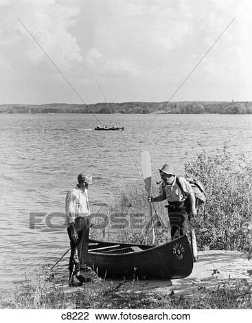 1940S 1950S Two Men Standing By River Next To Canoe One Man Holding Oar Lake Of The Woods Ontario Canada View Large Photo Image Stock Image - 1940S 1950S Two Men Standing By River Next To Canoe One Man Holding Oar Lake Of The Woods Ontario Canada. Fotosearch