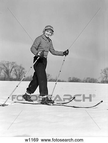 1940S 1950S Woman Smiling At Camera On Skis With Ski Pole In Each Hand Wearing Quilted Jacket View Large Photo Image Stock Photo - 1940S 1950S Woman Smiling At Camera On Skis With Ski Pole In Each Hand Wearing Quilted Jacket. Fotosearch