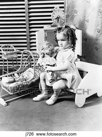1940S 3 Year Old Girl Sitting Holding Baby Doll Toy Cradle Toy High Chair & Toy Clock Venetian Blinds View Large Photo Image Stock Photograph - 1940S 3 Year Old Girl Sitting Holding Baby Doll Toy Cradle Toy High Chair & Toy Clock Venetian Blinds . Fotosearch