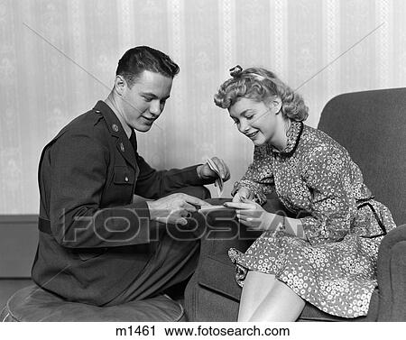 1940S A Wartime Romance Couple Man In Military Uniform Woman In Print Dress Sitting In Chair Smiling Looking At Papers View Large Photo Image Stock Image - 1940S A Wartime Romance Couple Man In Military Uniform Woman In Print Dress Sitting In Chair Smiling Looking At Papers . Fotosearch