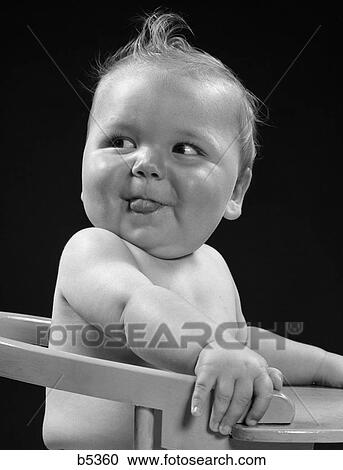 1940S Baby In High Chair Head Turned To One Side With Tongue Sticking Out Silly Happy Funny Expression View Large Photo Image Stock Image - 1940S Baby In High Chair Head Turned To One Side With Tongue Sticking Out Silly Happy Funny Expression . Fotosearch