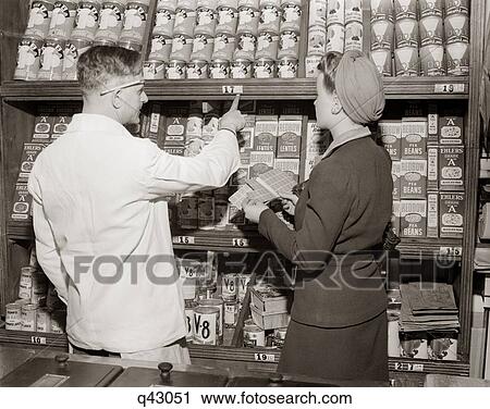 1940S Back View Of Grocer Pointing Out Prices Of Canned Goods To Woman Holding Ration Book View Large Photo Image Stock Image - 1940S Back View Of Grocer Pointing Out Prices Of Canned Goods To Woman Holding Ration Book . Fotosearch