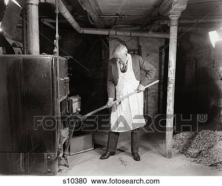 1940S Elderly Man In Basement Wearing Apron Shoveling Coal Into Furnace View Large Photo Image Stock Image - 1940S Elderly Man In Basement Wearing Apron Shoveling Coal Into Furnace . Fotosearch