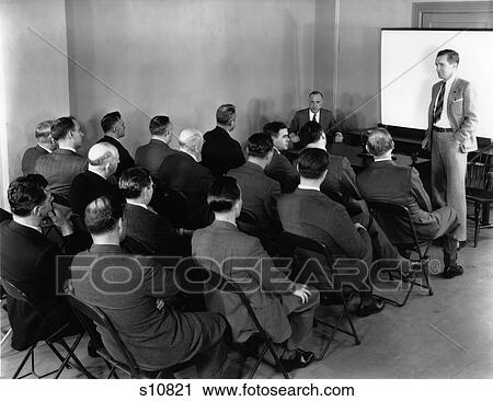 1940S Executives In Rows Of Folding Chairs At Meeting With Chairman In Front Of Room Banging Gavel On Table View Large Photo Image Stock Image - 1940S Executives In Rows Of Folding Chairs At Meeting With Chairman In Front Of Room Banging Gavel On Table . Fotosearch