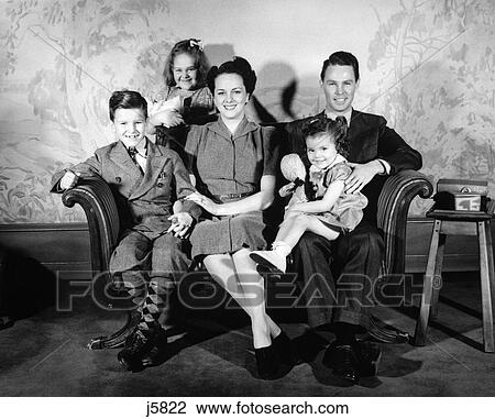 1940S Family Of 5 Portrait Sitting On Couch Facing Camera Smiling Mother Father Two Girls One Boy Wallpaper Print In Background View Large Photo Image Stock Image - 1940S Family Of 5 Portrait Sitting On Couch Facing Camera Smiling Mother Father Two Girls One Boy Wallpaper Print In Background. Fotosearch