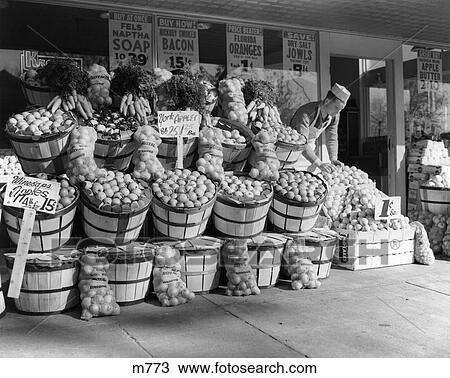 1940S Grocer In White Cap & Apron Setting Out Fruit On Sidewalk In Front Of Grocery Store View Large Photo Image Stock Image - 1940S Grocer In White Cap & Apron Setting Out Fruit On Sidewalk In Front Of Grocery Store . Fotosearch