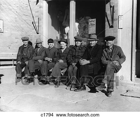 Picture - 1940S Group Of Old Men In Hats & Dungarees Sitting On Bench In Front Of Store Window . Fotosearch
