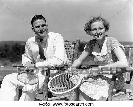 1940S Man And Woman Sitting In Wooden Chairs Each Holding Tennis Raquet Racket View Large Photo Image Stock Photography - 1940S Man And Woman Sitting In Wooden Chairs Each Holding Tennis Raquet Racket . Fotosearch