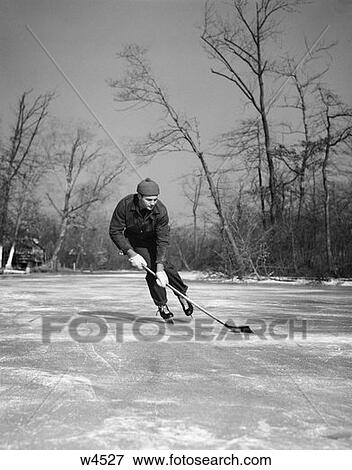 1940S Man Playing Ice Hockey On Frozen Lake Controlling Puck With Stick Trees In Bakground Skate View Large Photo Image Stock Photo - 1940S Man Playing Ice Hockey On Frozen Lake Controlling Puck With Stick Trees In Bakground Skate . Fotosearch