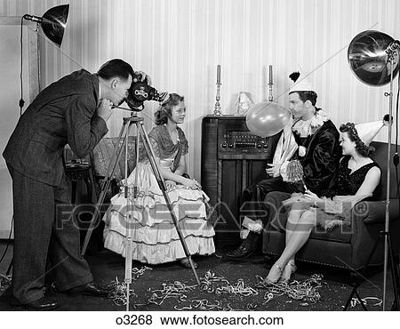 1940S Photographer Taking Picture Of Two Women & A Man Wearing Costumes Man Blowing Up Balloon View Large Photo Image Stock Photo - 1940S Photographer Taking Picture Of Two Women & A Man Wearing Costumes Man Blowing Up Balloon . Fotosearch