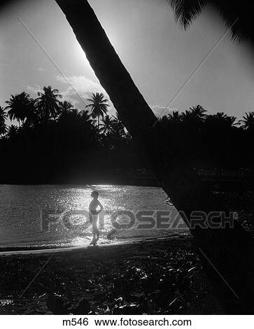 1940S Silhouette Of Woman Standing On Tropical Shore With Ray Of Light Coming In On Water Behind Her View Large Photo Image Stock Photograph - 1940S Silhouette Of Woman Standing On Tropical Shore With Ray Of Light Coming In On Water Behind Her . Fotosearch