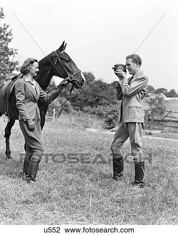 1940S Smiling Equestrian Couple The Woman Is Holding The Horses Bridle The Man Is Taking Movies Of Them View Large Photo Image Stock Image - 1940S Smiling Equestrian Couple The Woman Is Holding The Horses Bridle The Man Is Taking Movies Of Them . Fotosearch
