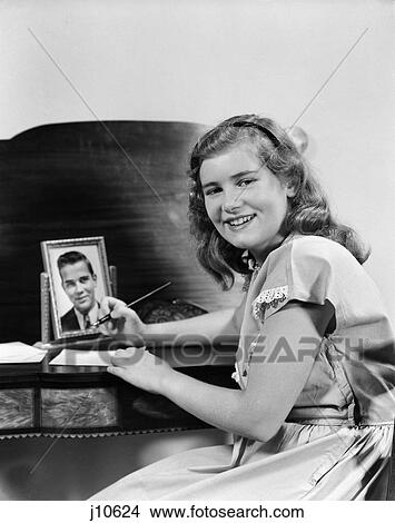 1940S Smiling Girl At Desk Writing Letter Photo Of Boy Or Man In Frame View Large Photo Image Picture - 1940S Smiling Girl At Desk Writing Letter Photo Of Boy Or Man In Frame . Fotosearch
