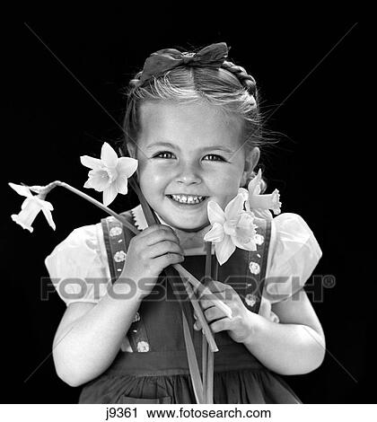 Stock Image - 1940S Smiling Girl Holding Spring Daffodils Wearing Jumper With Hair Braid Held On Top Of Head With Bow . Fotosearch