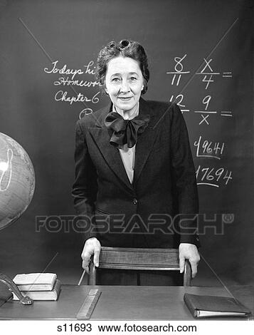 1940S Smiling School Teacher Standing Behind Her Desk & In Front Of The Black Board With Fractions View Large Photo Image Stock Image - 1940S Smiling School Teacher Standing Behind Her Desk & In Front Of The Black Board With Fractions . Fotosearch