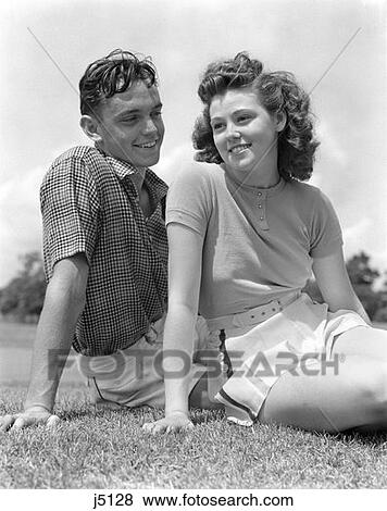 Stock Photo - 1940S Smiling Teen Couple Sitting In Grass Portrait . Fotosearch