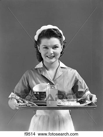 1940S Smiling Waitress Wearing A Cap & Uniform With White Collar & Apron Holding A Serving Tray View Large Photo Image Picture - 1940S Smiling Waitress Wearing A Cap & Uniform With White Collar & Apron Holding A Serving Tray . Fotosearch