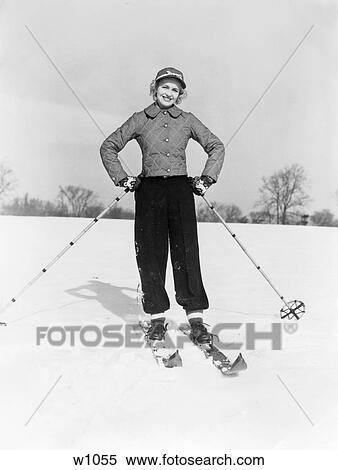 Stock Photography - 1940S Smiling Woman On Skis With Cap And Quilted Ski Jacket With Both Hands On Hips . Fotosearch