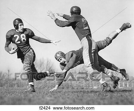 1940S Three Men Playing Football Leather Helmets One Man Tackles Another Who Is Trying To Intercept The Third Outdoor View Large Photo Image Picture - 1940S Three Men Playing Football Leather Helmets One Man Tackles Another Who Is Trying To Intercept The Third Outdoor . Fotosearch