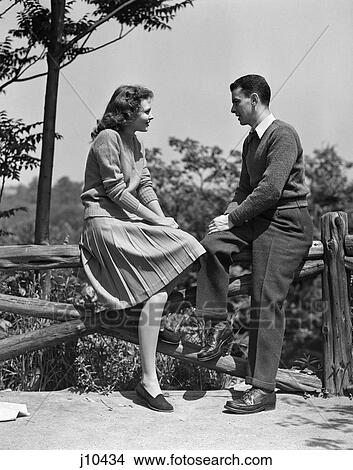 Picture - 1940S Young Couple Teen Sitting Talking On Wooden Fence . Fotosearch