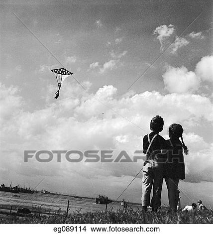 1940S Young Girl And Boy Standing Side By Side Flying Patriotic Flag Kite Over River View Large Photo Image Picture - 1940S Young Girl And Boy Standing Side By Side Flying Patriotic Flag Kite Over River. Fotosearch