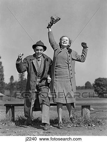 1940S Young Teen Couple Boy Girl Bench Wearing Coats Cheering At Sporting Event Excited Happy Spectators View Large Photo Image Stock Image - 1940S Young Teen Couple Boy Girl Bench Wearing Coats Cheering At Sporting Event Excited Happy Spectators . Fotosearch