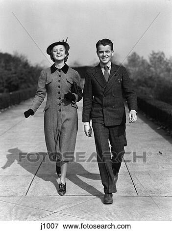 1940S Young Teen Couple Walking Down Sidewalk Smiling Dressed Up Sunday Best Boy Wear Suit Girl Coat And Hat View Large Photo Image Stock Photo - 1940S Young Teen Couple Walking Down Sidewalk Smiling Dressed Up Sunday Best Boy Wear Suit Girl Coat And Hat . Fotosearch
