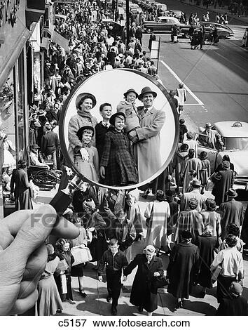 Stock Photo - 1950S Montage Of Family In Magnifying Glass Superimposed Over Crowded Sidewalk . Fotosearch