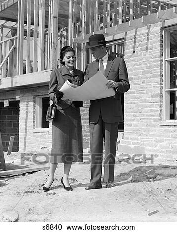 1950 1950S Couple Looking At Building Plans Standing In Front Of Unfinished House View Large Photo Image Stock Image - 1950 1950S Couple Looking At Building Plans Standing In Front Of Unfinished House . Fotosearch