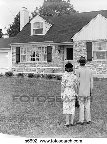 Stock Image - 1950 1950S Couple Standing Outside Looking At House . Fotosearch