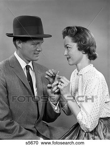 Stock Image - 1950 1950S Couple Woman Tying A Sting In A Bow Around Man'S Finger . Fotosearch