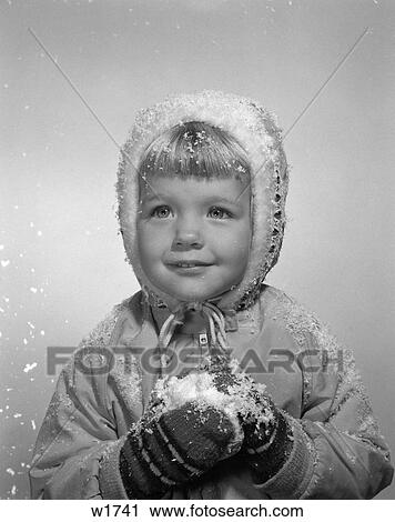 Stock Image - 1950 1950S Little Girl Posing In Winter Jacket Mittens And Holding Snow . Fotosearch
