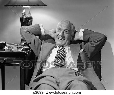 1950 1950S Older Man Lounging In Chair Wearing Suit Arms Behind Head View Large Photo Image Stock Photo - 1950 1950S Older Man Lounging In Chair Wearing Suit Arms Behind Head . Fotosearch