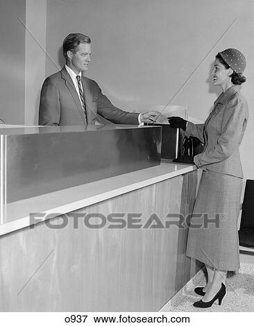 Stock Photo - 1950 1950S Retro Bank Teller Woman Man Partition Finance Money Suit Hat . Fotosearch