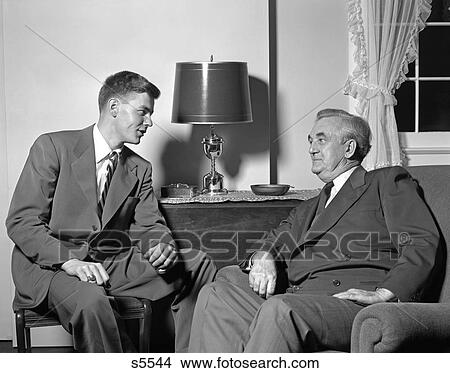 1950 1950S Two Men Sitting In Living Room Talking View Large Photo Image Picture - 1950 1950S Two Men Sitting In Living Room Talking . Fotosearch