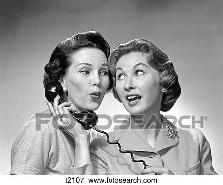 Stock Photo - 1950 1950S Two Woman One Holding Phone To Other'S Ear Gossip Expression . Fotosearch