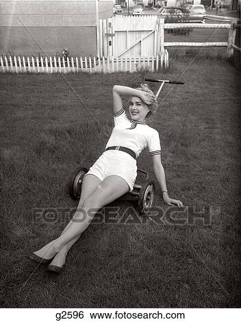 1950 1950S Woman Wearing White Short Shorts Lying On Top Of A Push Lawn Mower Looking Exhausted View Large Photo Image Stock Photograph - 1950 1950S Woman Wearing White Short Shorts Lying On Top Of A Push Lawn Mower Looking Exhausted . Fotosearch