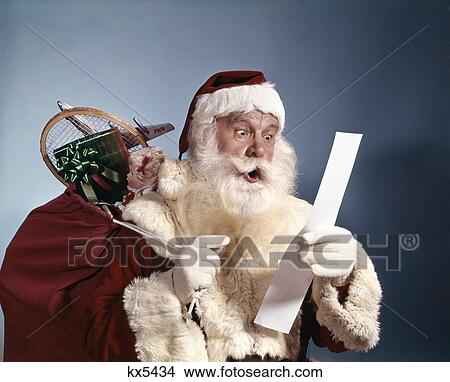 1950'S 1960'S 1970'S Surprised Santa Claus Carrying Sack Of Toys Reading List Studio Indoor View Large Photo Image Picture - 1950'S 1960'S 1970'S Surprised Santa Claus Carrying Sack Of Toys Reading List Studio Indoor. Fotosearch