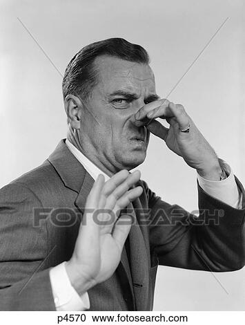 Stock Image - 1950S 1960S Man 3/4 Profile Hand Holding Nose Closed Hand Out Toward Camera Facial Expression Disgust Stinking. Fotosearch