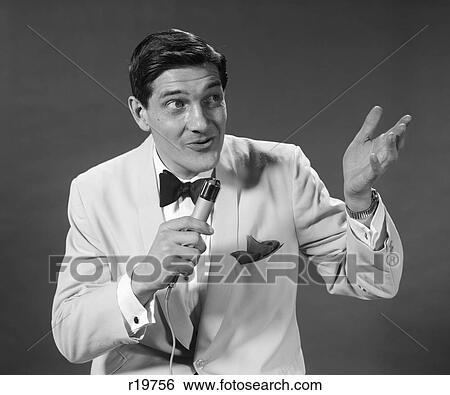 Stock Photograph - 1950S 1960S Man White Tuxedo Jacket Hold Microphone Sing Talk Gesture With Hand Performer Host Emcee . Fotosearch